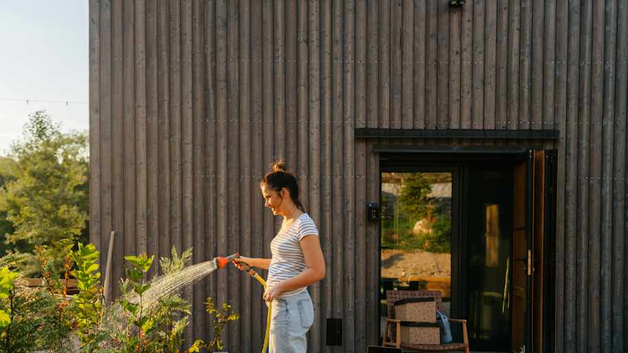 A woman watering her garden in front of her house 