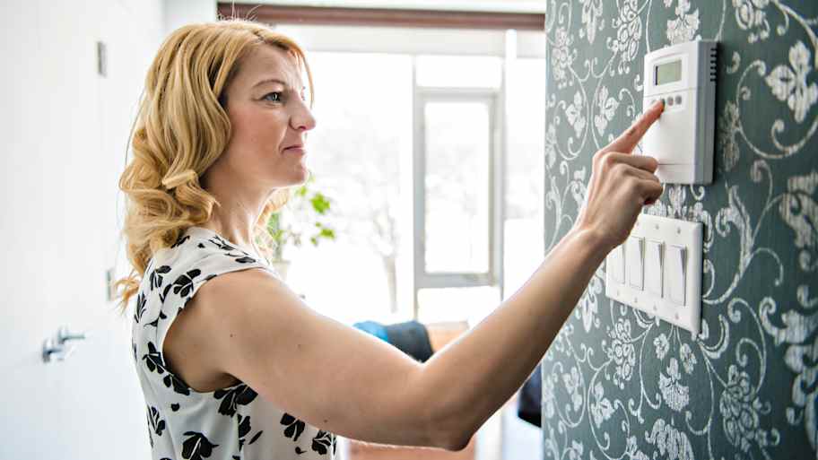 woman adjusting thermostat