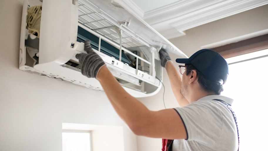 Technician installing a mini-split AC unit in the house