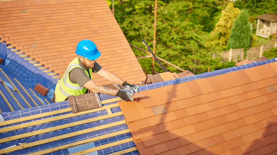 A roofer installing new clay tiles on a house 