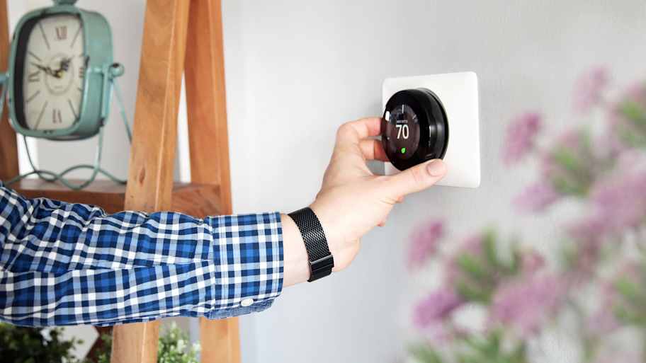 Person adjusting room temperature on a thermostat 