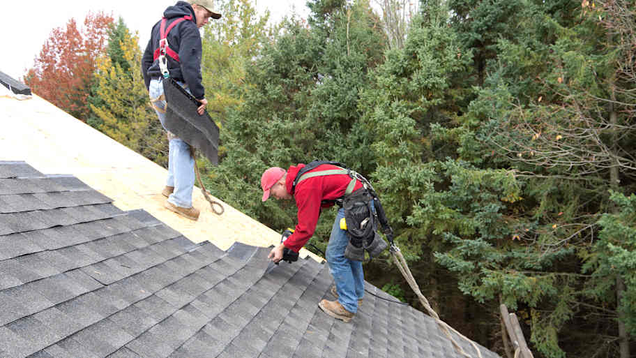 Workers installing new asphalt shingles on the roof 