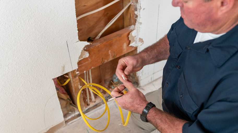 Electrician working on wiring in wall