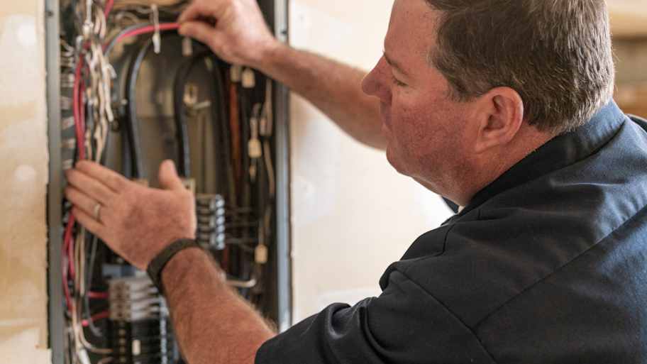 Electrician working on circuit breaker box