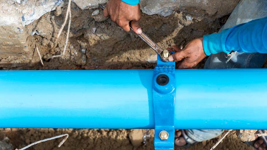Man using a large wrench on water pipes