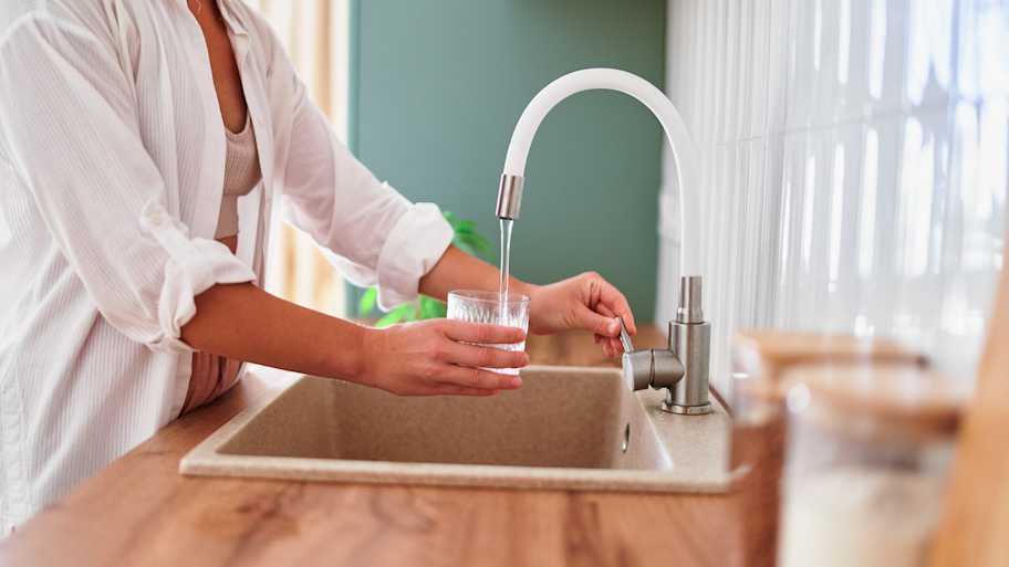 Woman in the kitchen filling a glass with tap water  