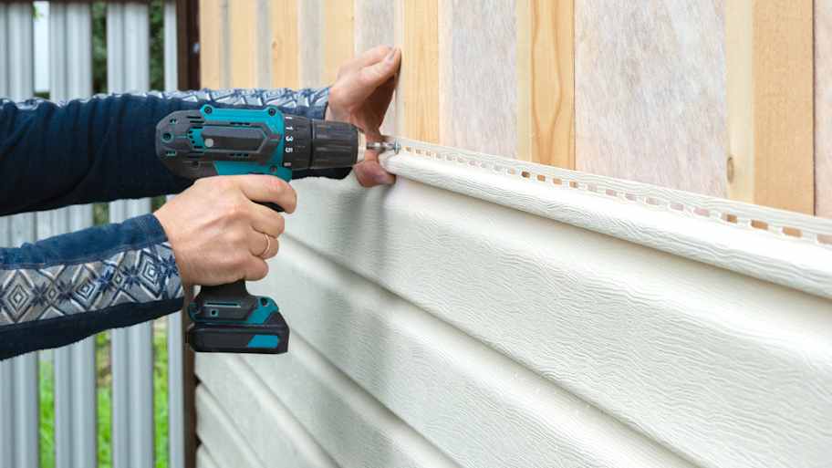Worker attaching new vinyl siding to the house   