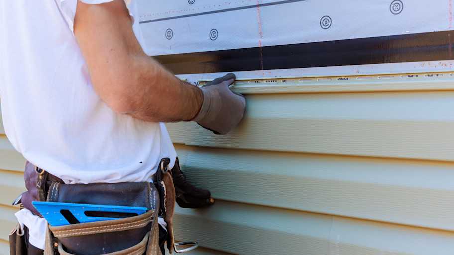 Handyman process installing vinyl PVC siding during construction on facade new home