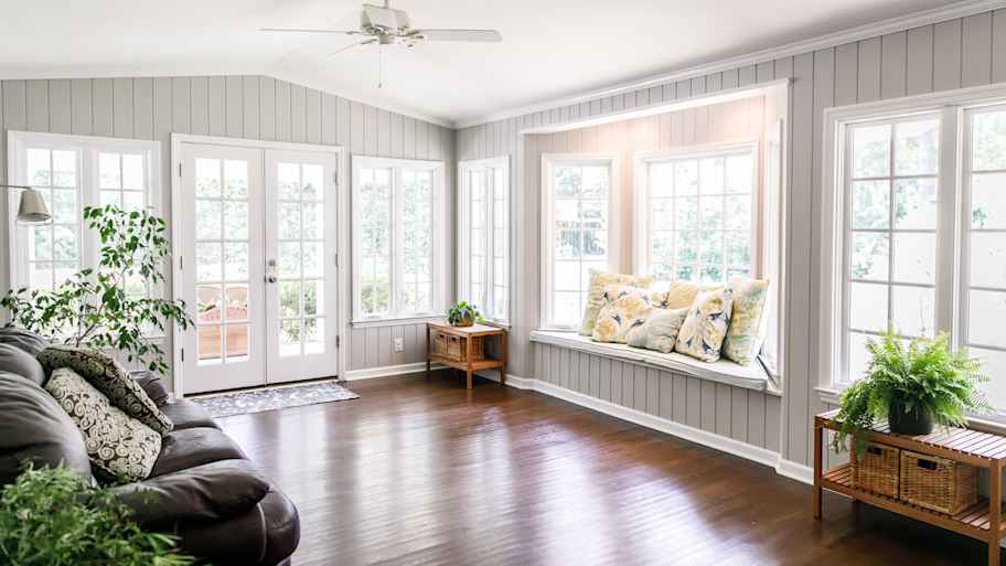 The interior of a bright living room with large windows