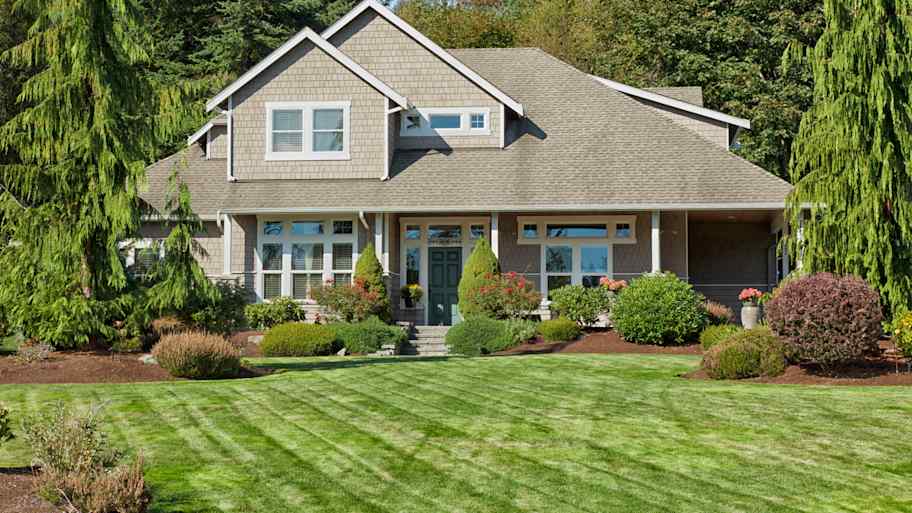 A two-story house with lawn and landscaped yard 