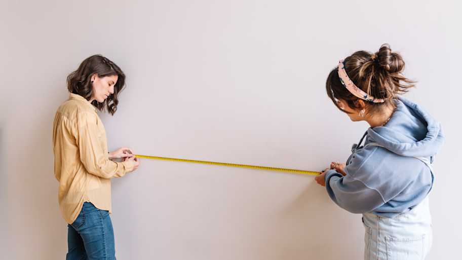 Two women measuring wall 