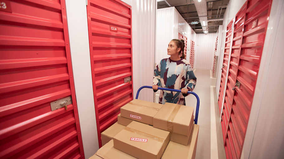 woman walking toward storage unit with labeled boxes 