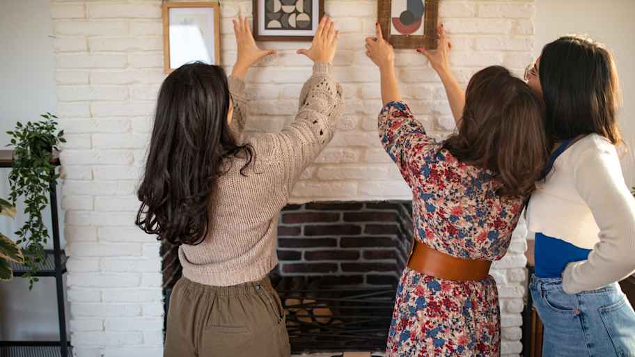 women helping each other hang pictures