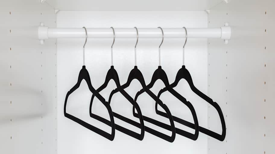 Dark black velvet empty hangers without clothes on rail