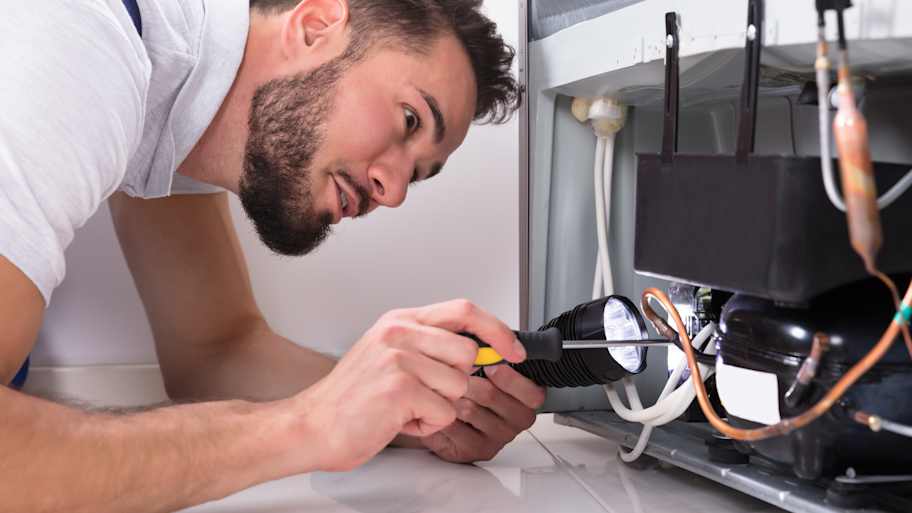 A technician fixing a freon leak of a refrigerator