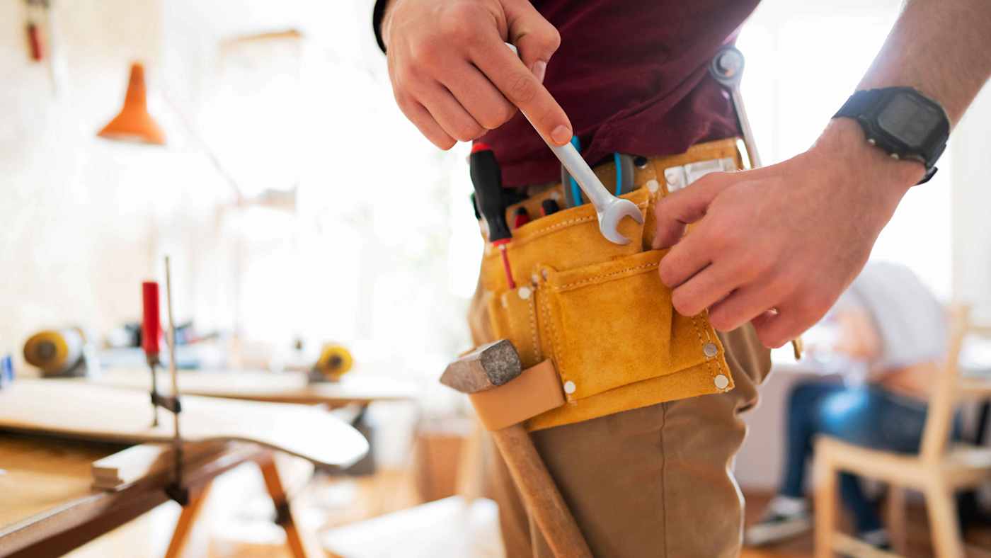Person putting a wrench in their tool belt