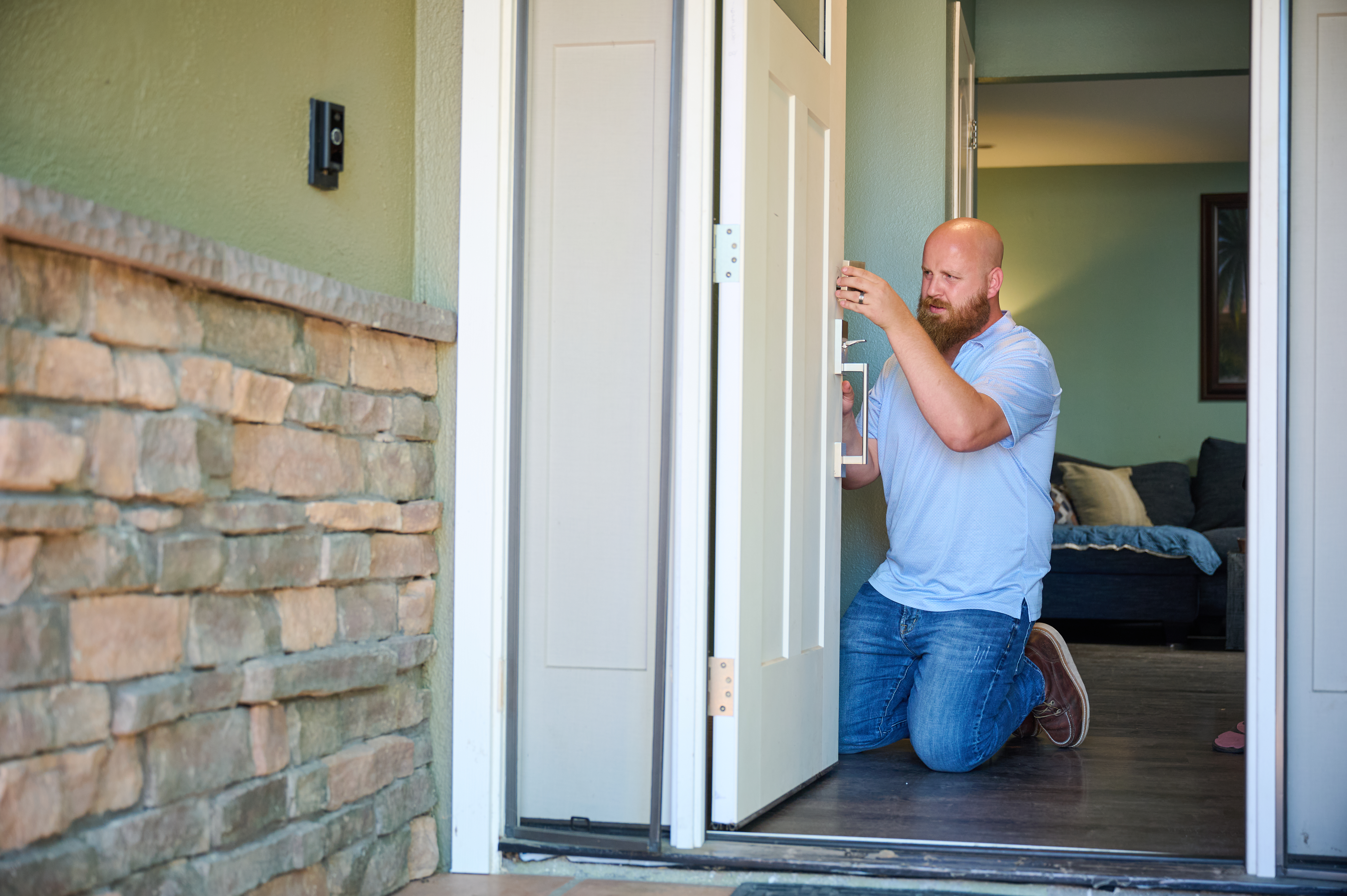 Handyman Chris McNeill from C.A. Shamrock LLC  installs a new door handle on an entry door, ensuring it aligns properly for smooth operation and security.