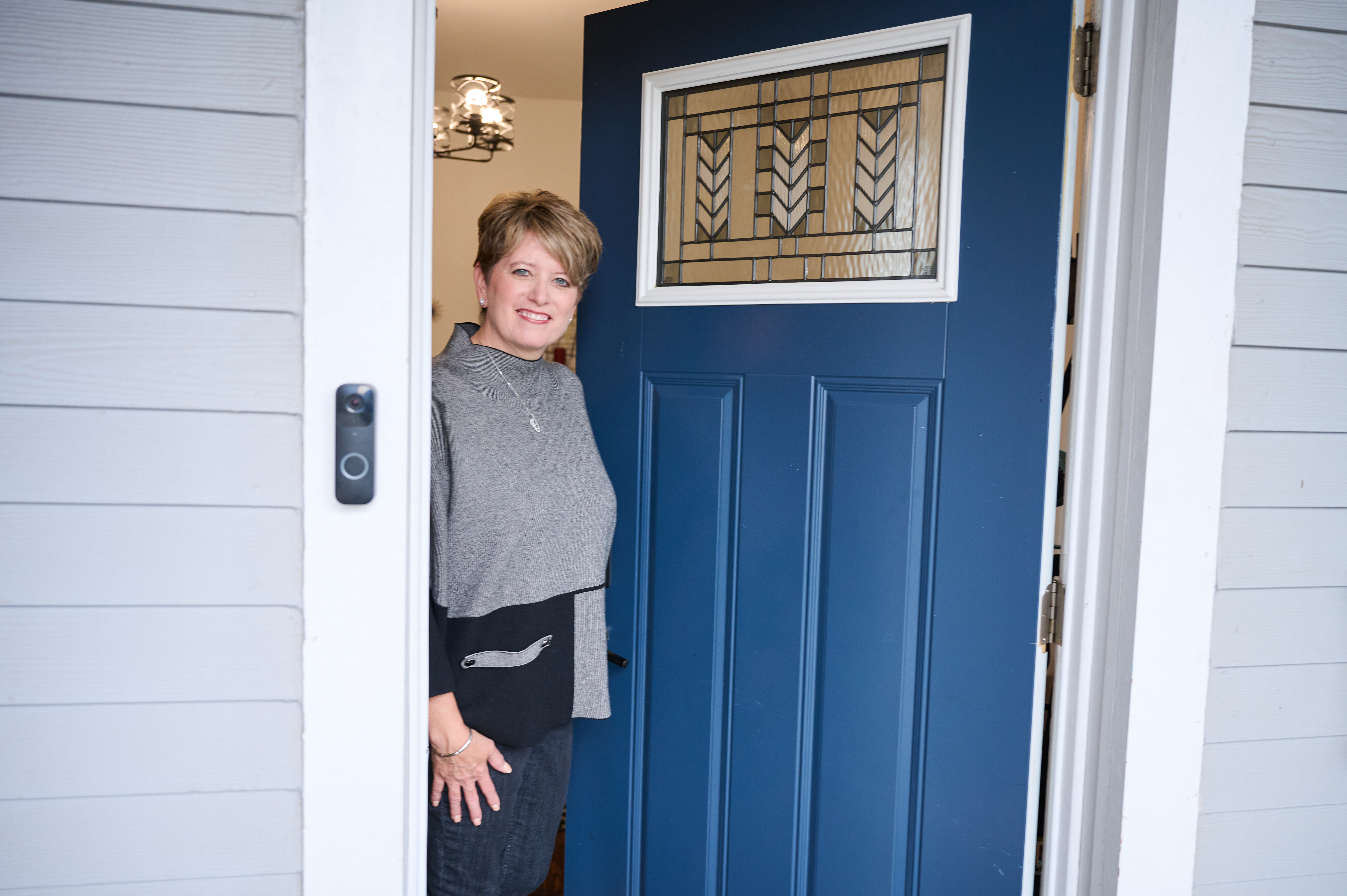 Angie Hicks opening the front door of a home Hicks sitting on the front porch