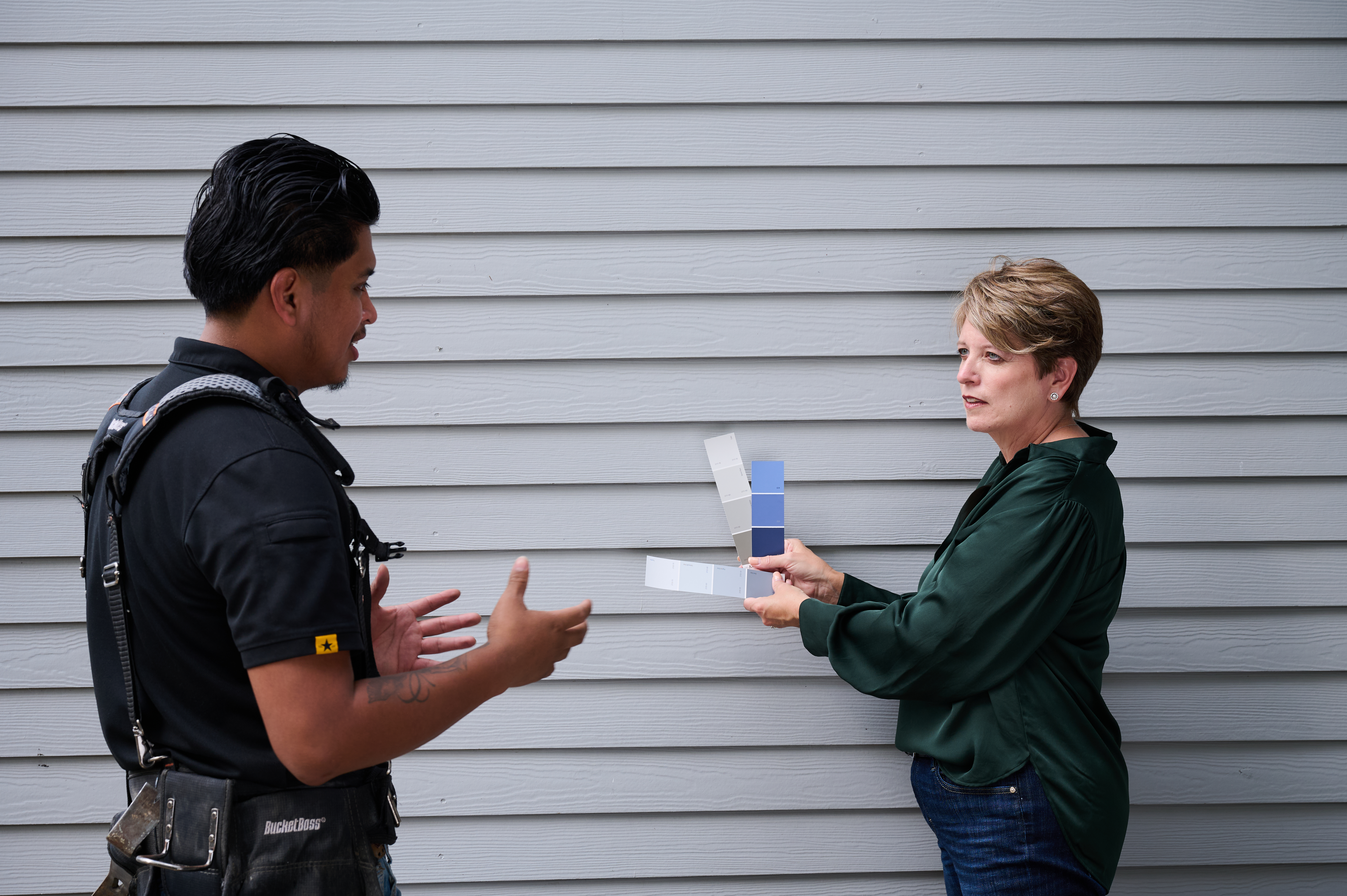 Angie Hicks shows paint swatches to the pro painting the siding