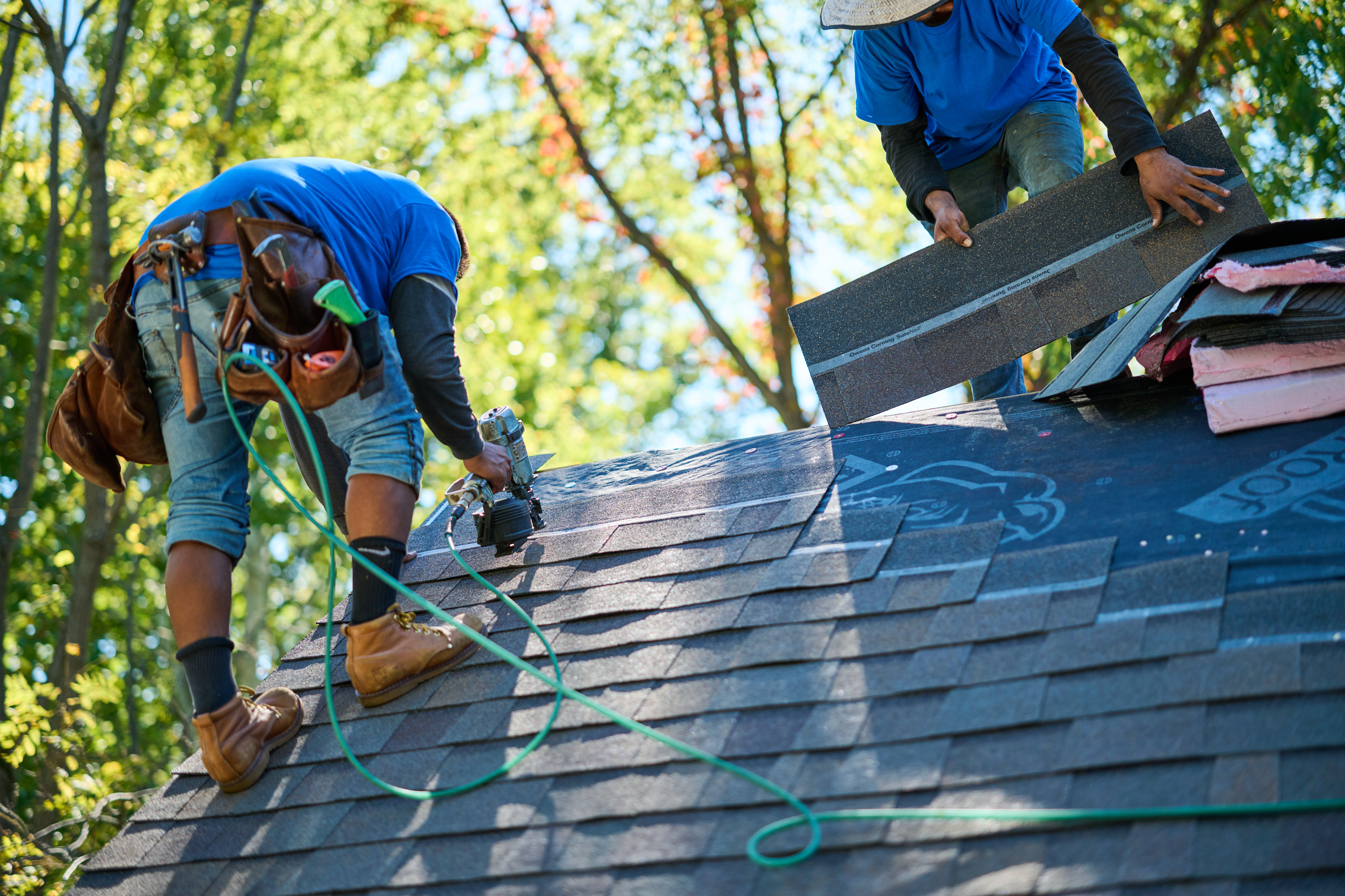 Men applying shingles to rooftop.