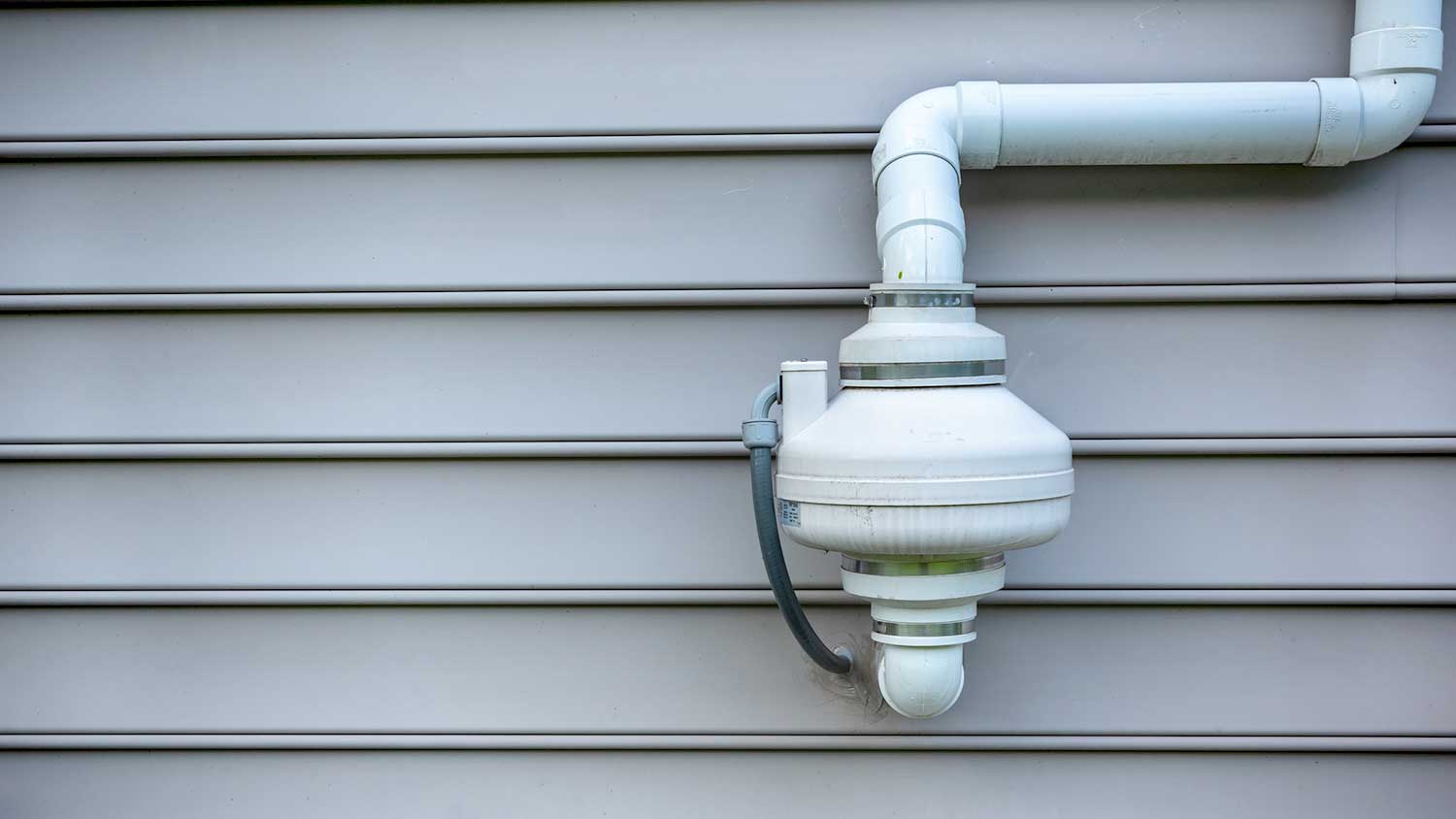 Radon mitigation fan attached to outdoor wall