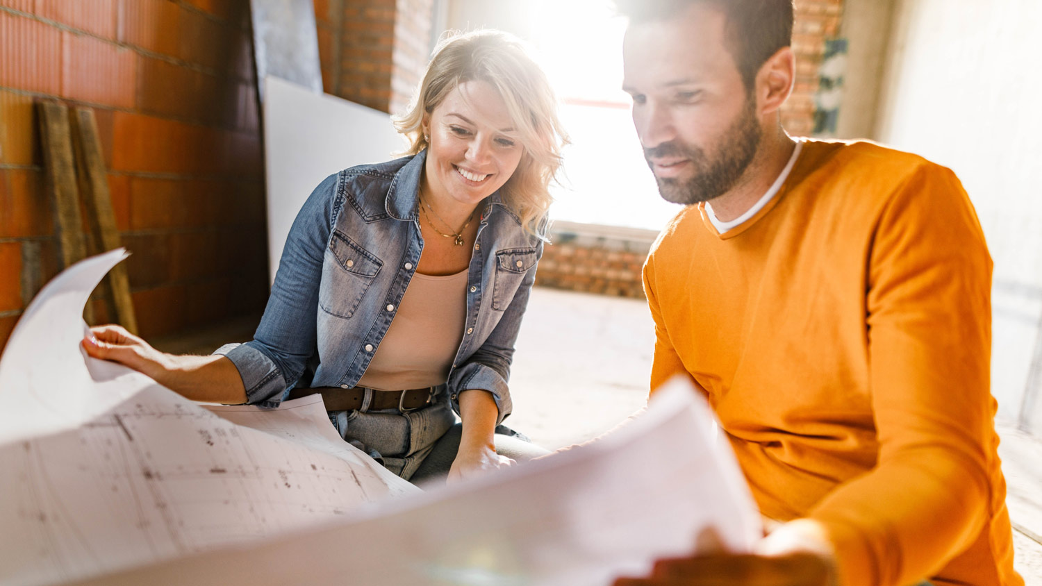 A young couple looking at plans while renovating a room in their house