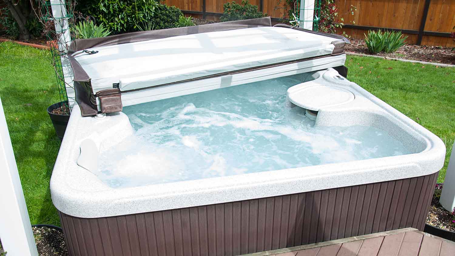 Hard hot tub cover opened halfway sitting on top of a hot tub
