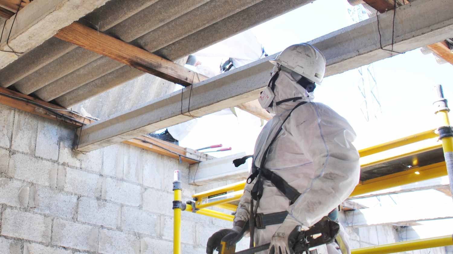 Worker removing asbestos from roof