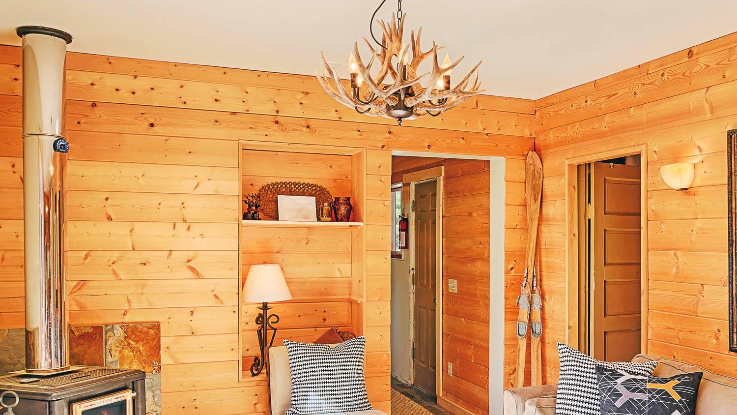 Wood paneling and antler chandelier in rustic living room