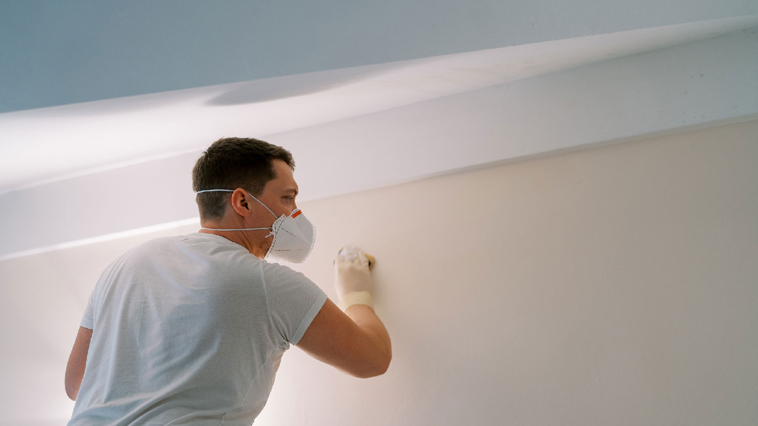 A man cleaning mold off the wall