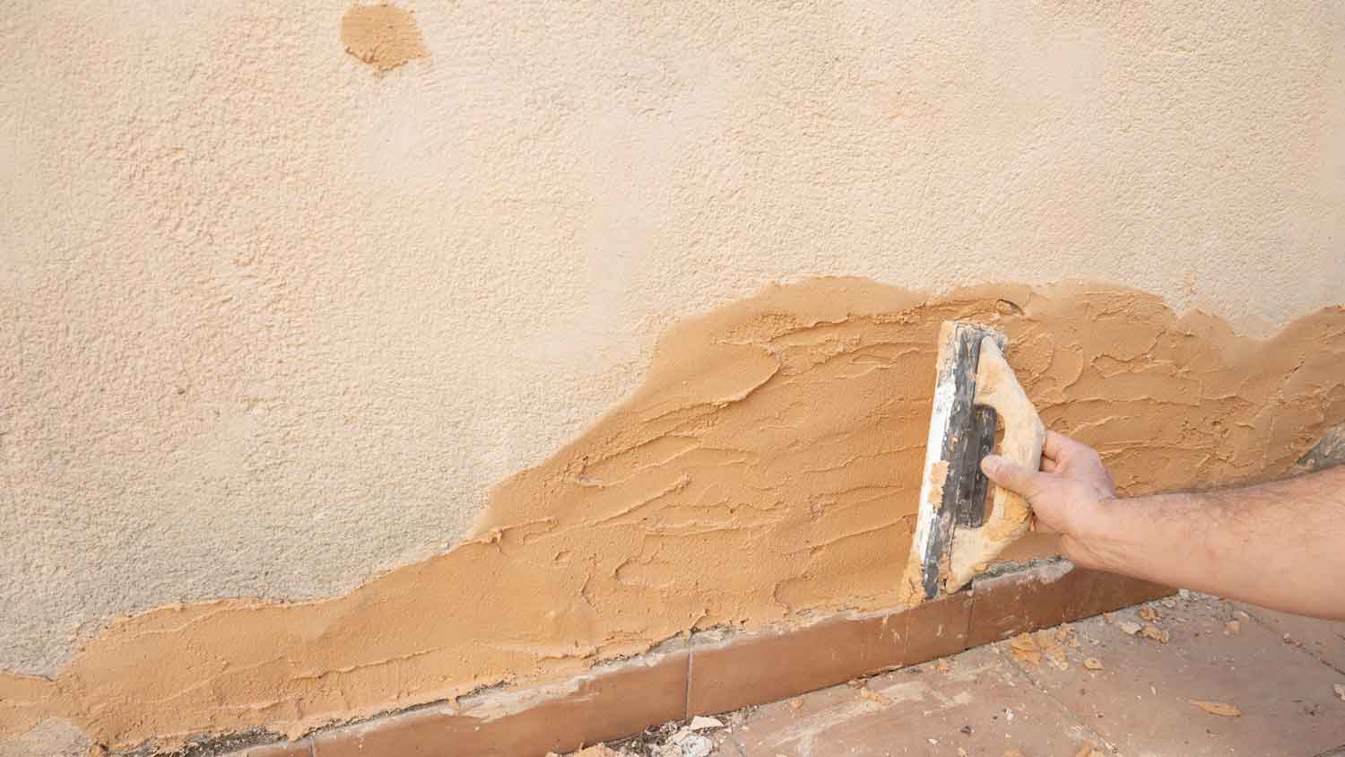 A person applying clay plaster with a trowel