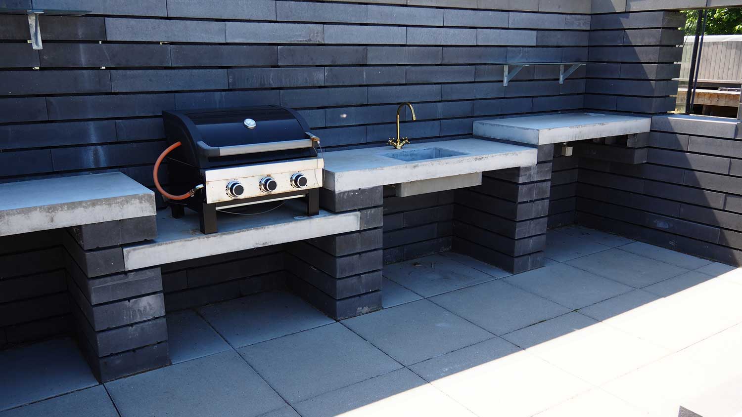 An outdoor kitchen with a gas line connected to a grill