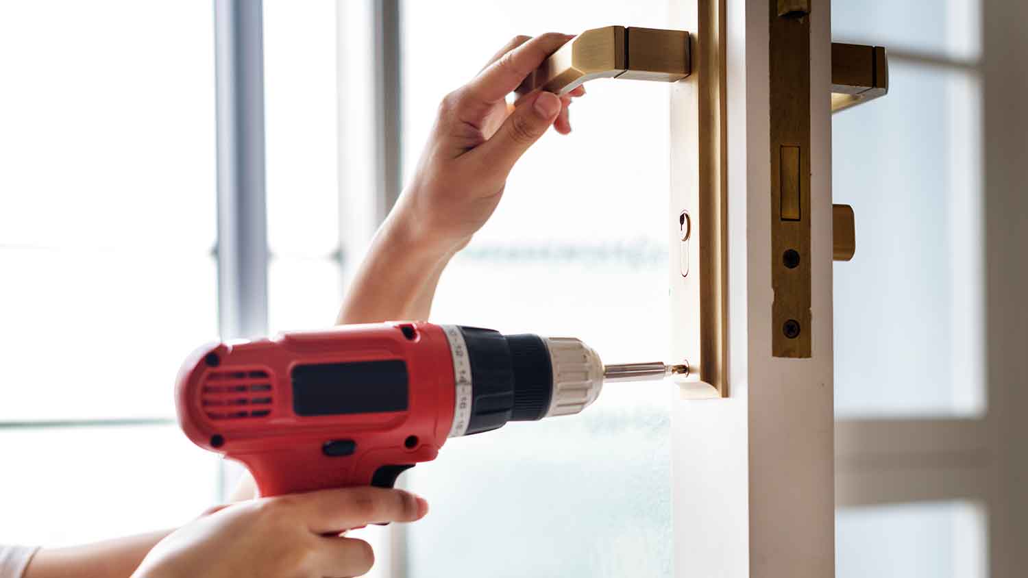 Woman using drill to install new door handle