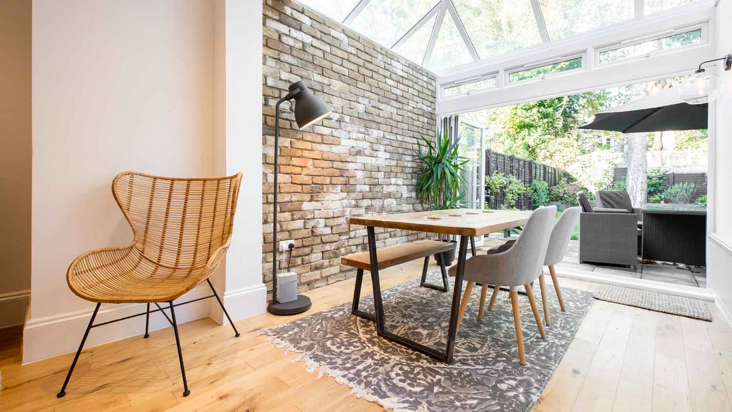 A living room with a brick wall and an extension with a glass conservatory room