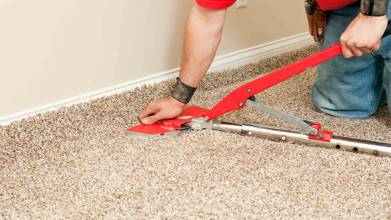 man using carpet stretcher in room