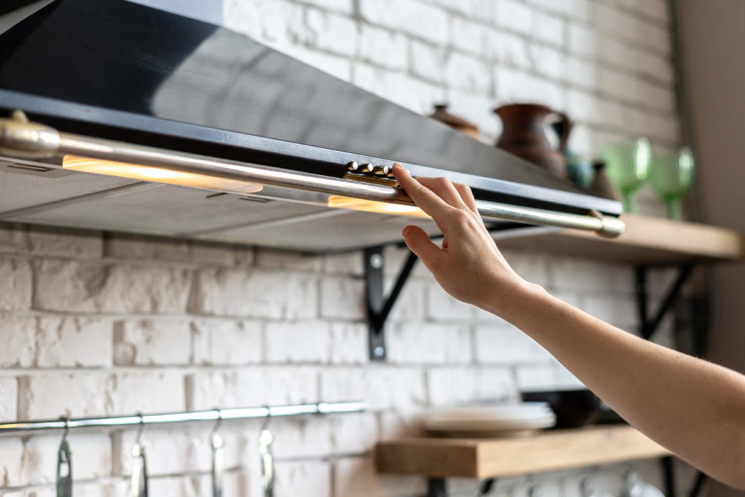 Woman hand selecting mode on range hood in the kitchen