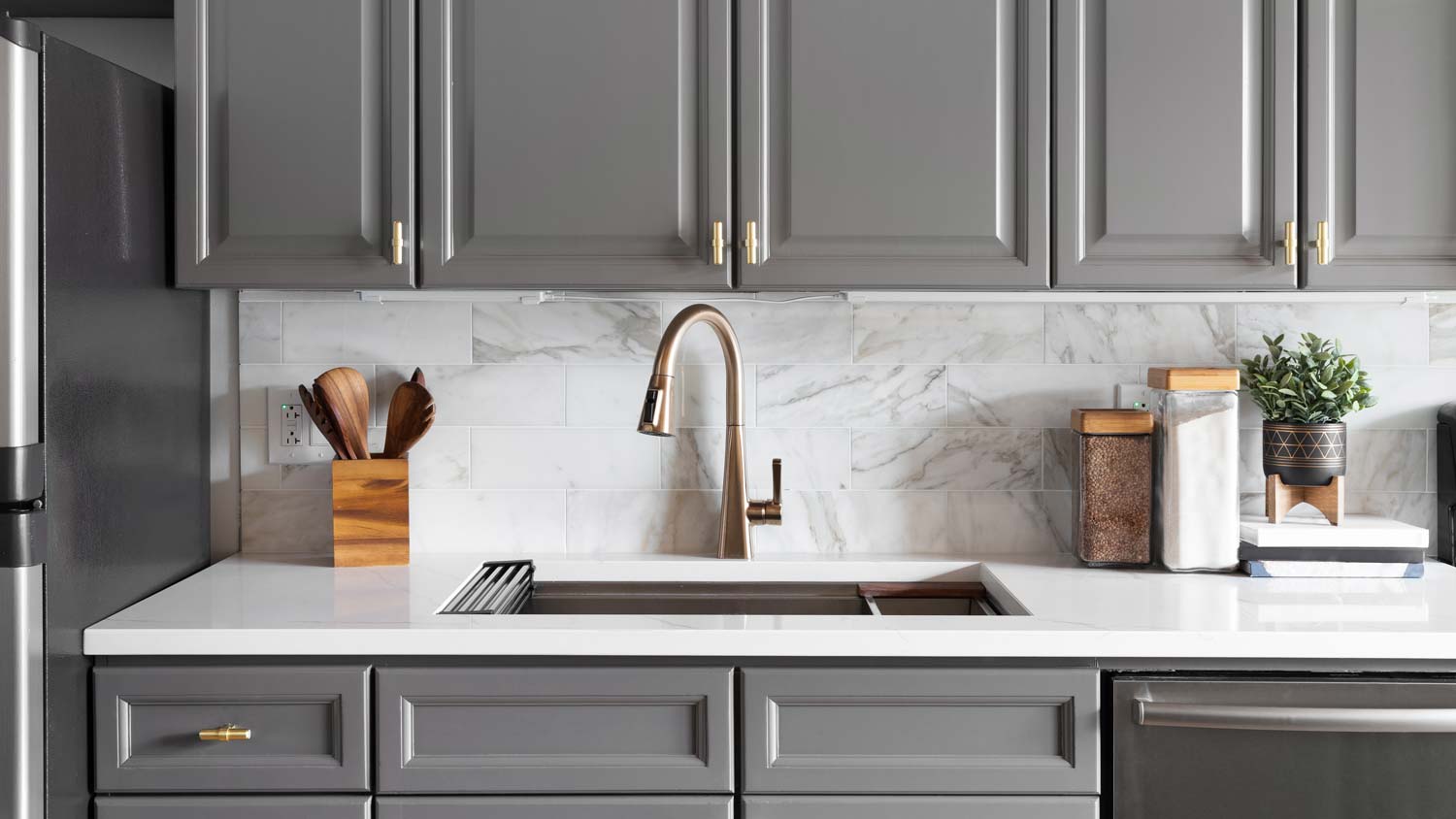 A kitchen with gray cabinets and an undermount sink