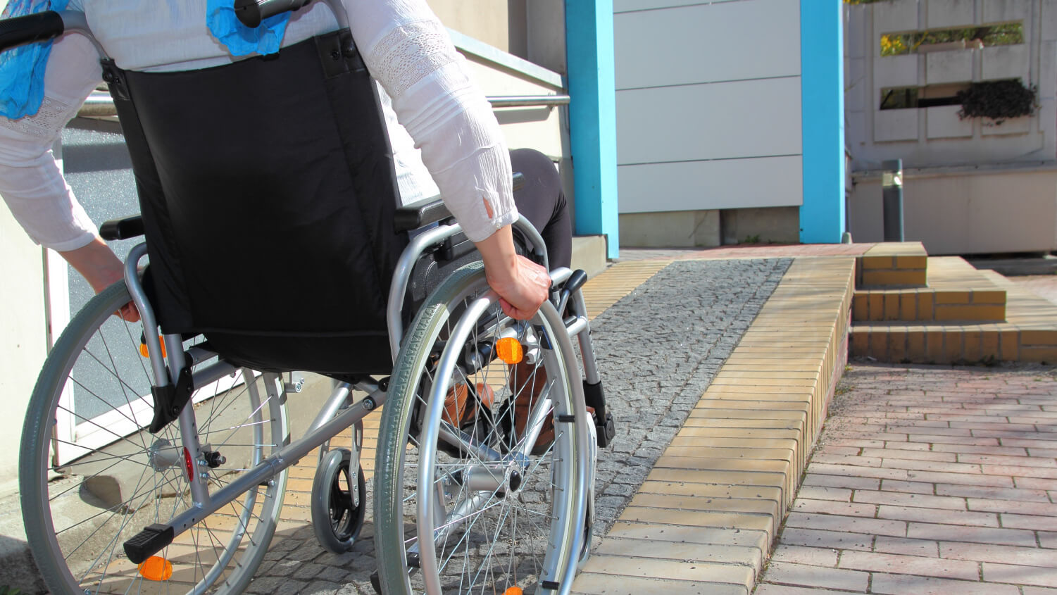 woman using wheel chair ramp outside home