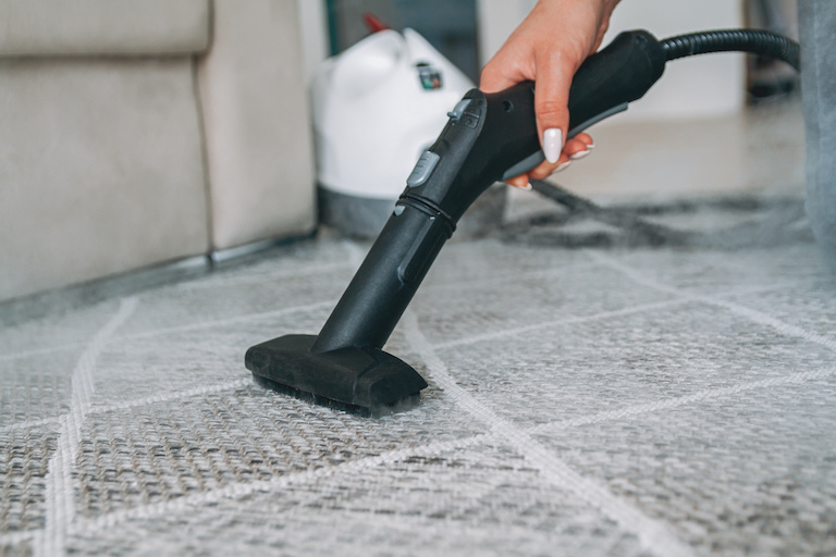 a steam cleaner cleaning a gray and white carpet with steam in the air