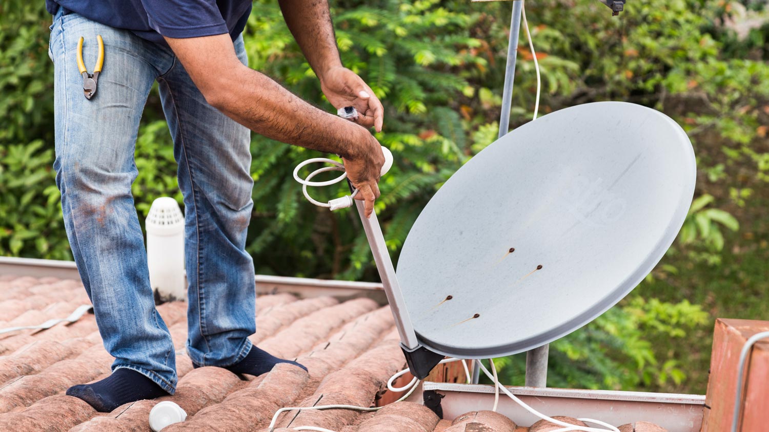 A man removing a satellite dish from a roof