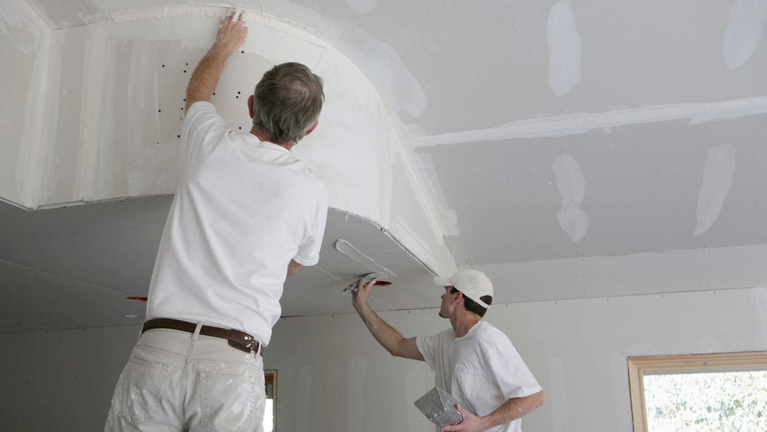 Workers applying mud to drywall