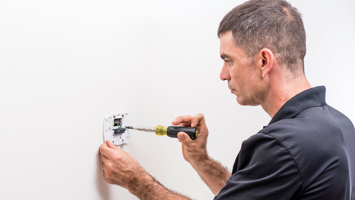 HVAC technician installing new thermostat