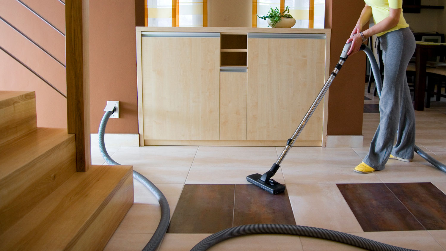 A woman cleaning the living room with a central vacuum