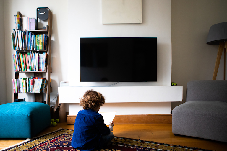 wall mounted tv in living room with small child sitting on ground