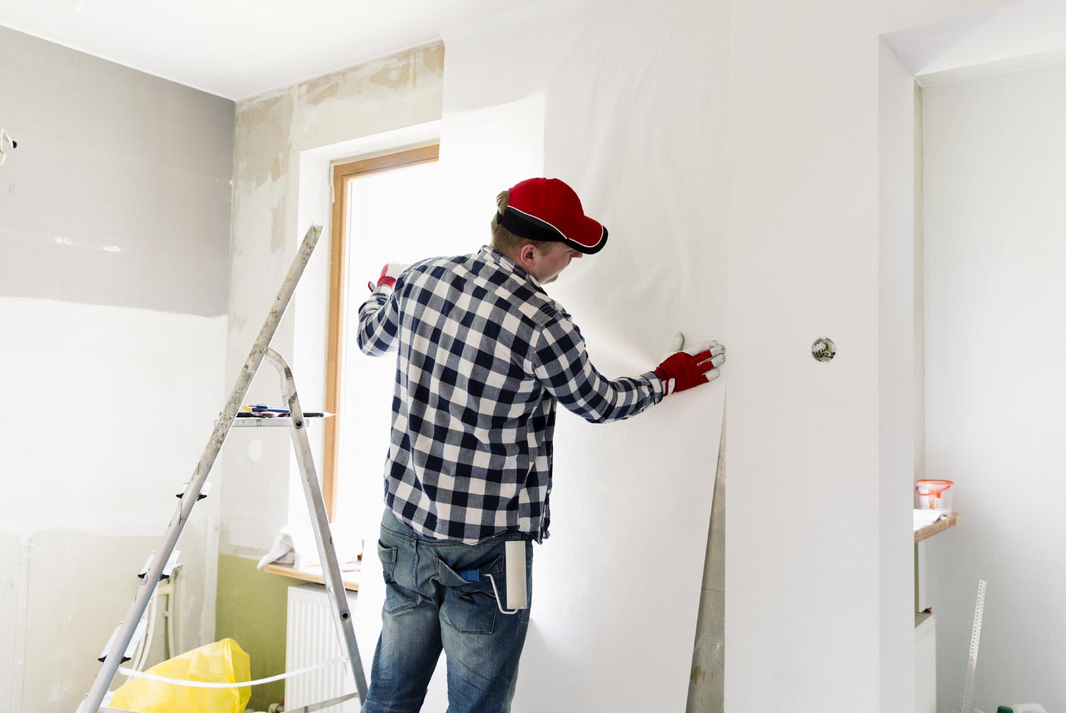 A worker putting up wallpapers on the wall.