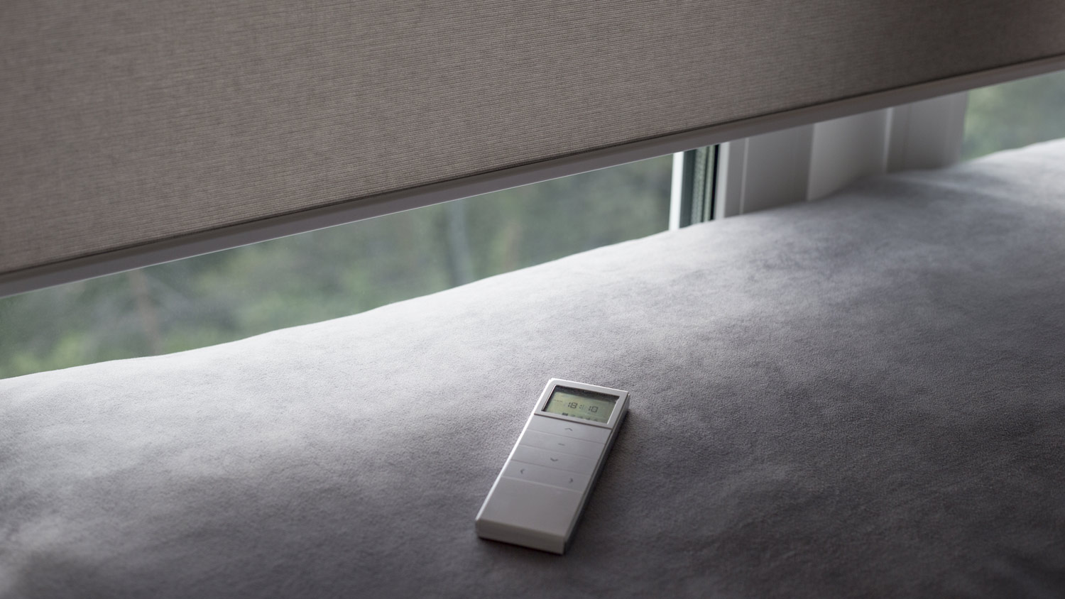 Motorized window roller blinds with the remote controller on a sofa