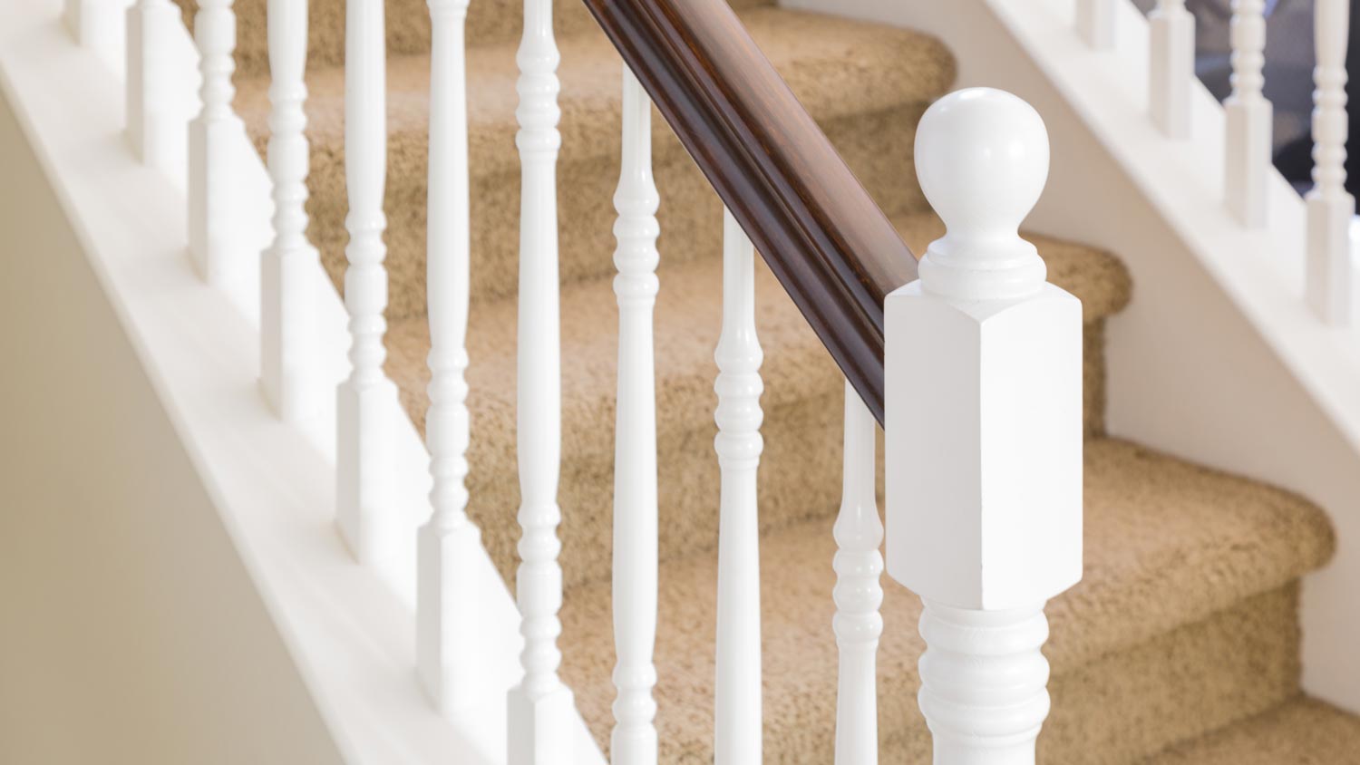 A wooden stair railing on carpeted steps