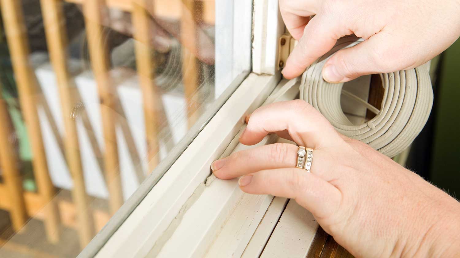 Woman installing weatherstrip around the window