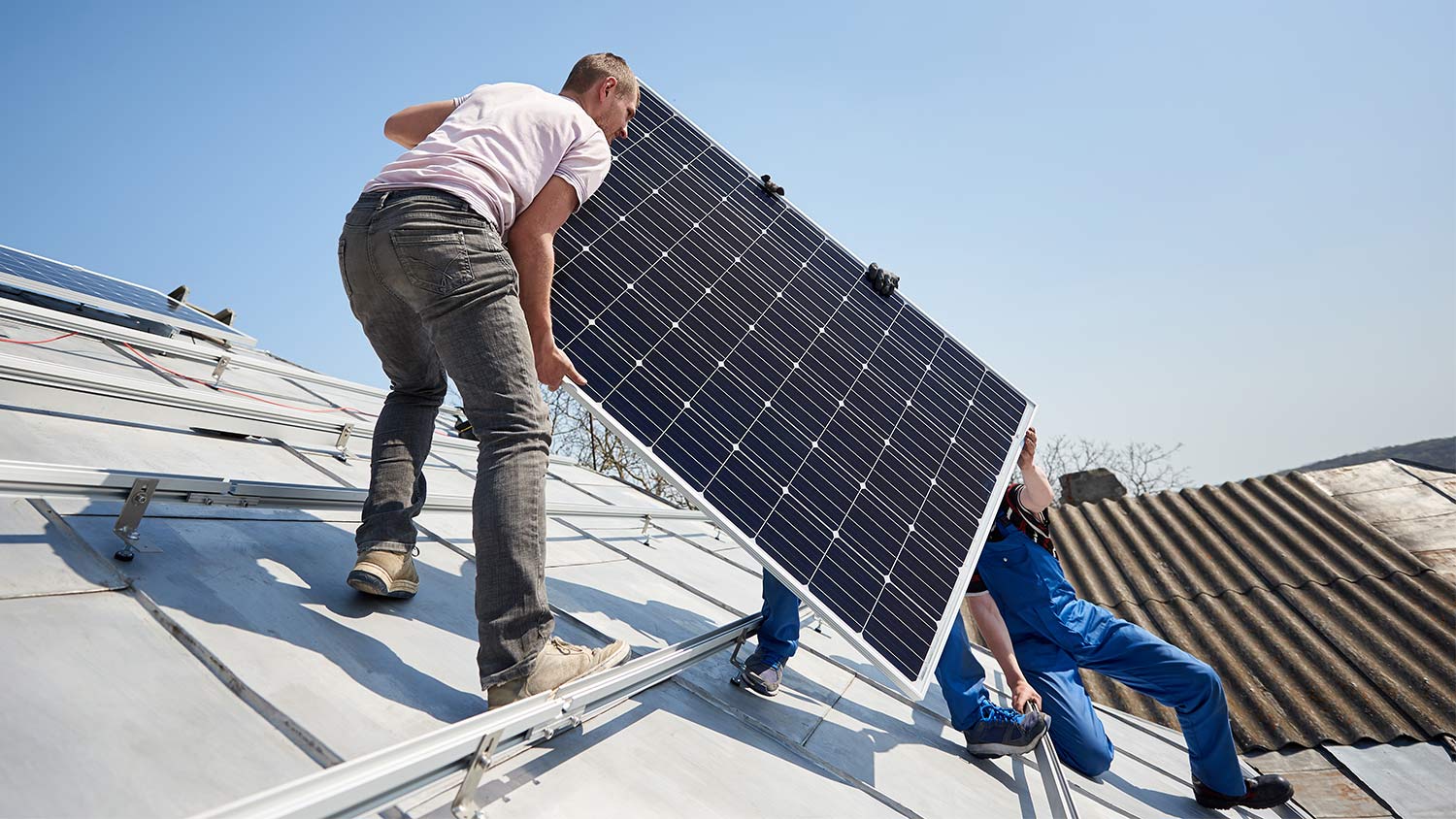 Men install solar panel on roof