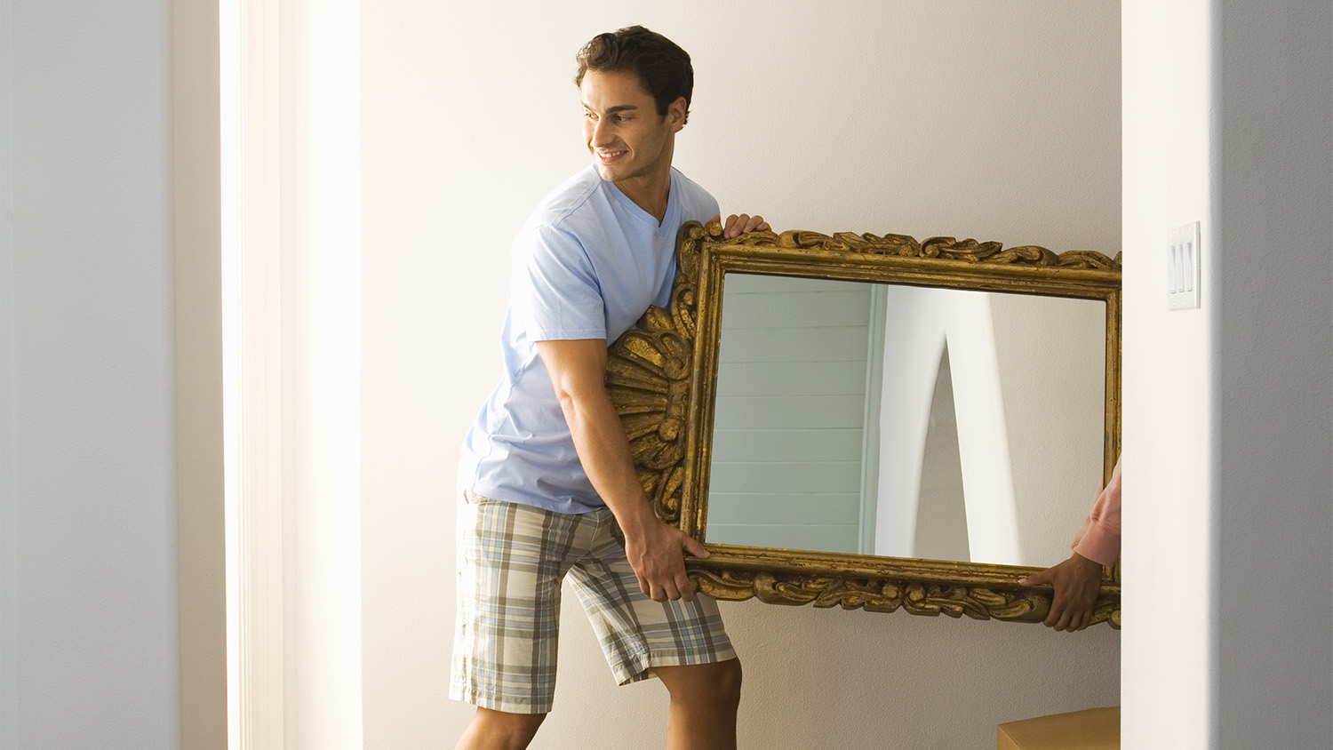 man moving wall mirror